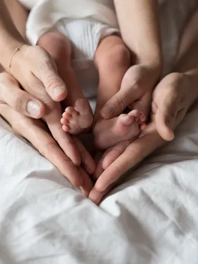 Twee handen houden de voetjes van een pasgeboren baby vast